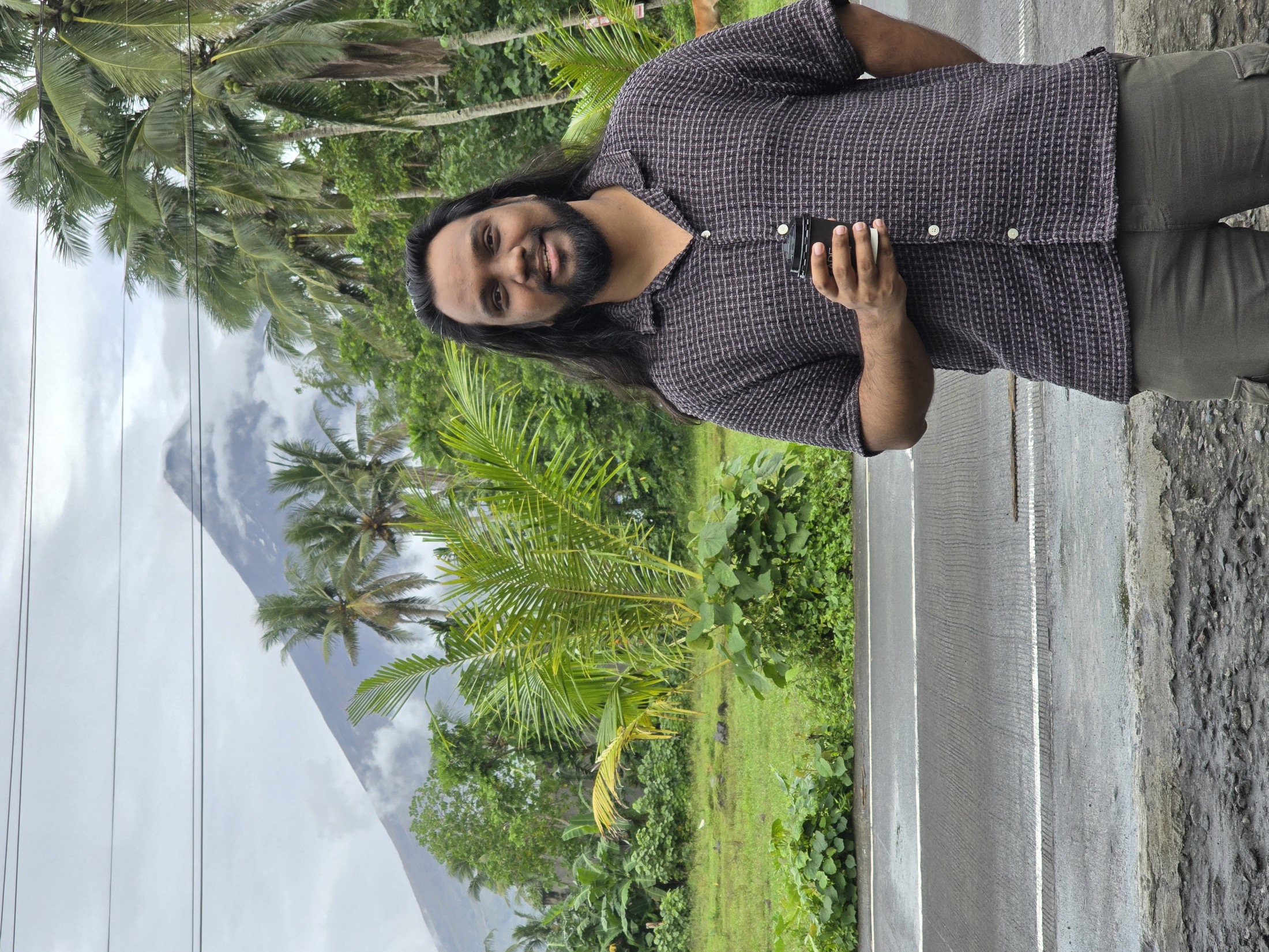 Suniv Ashraf in front of a cloud-covered volcano and tropical landscape.
