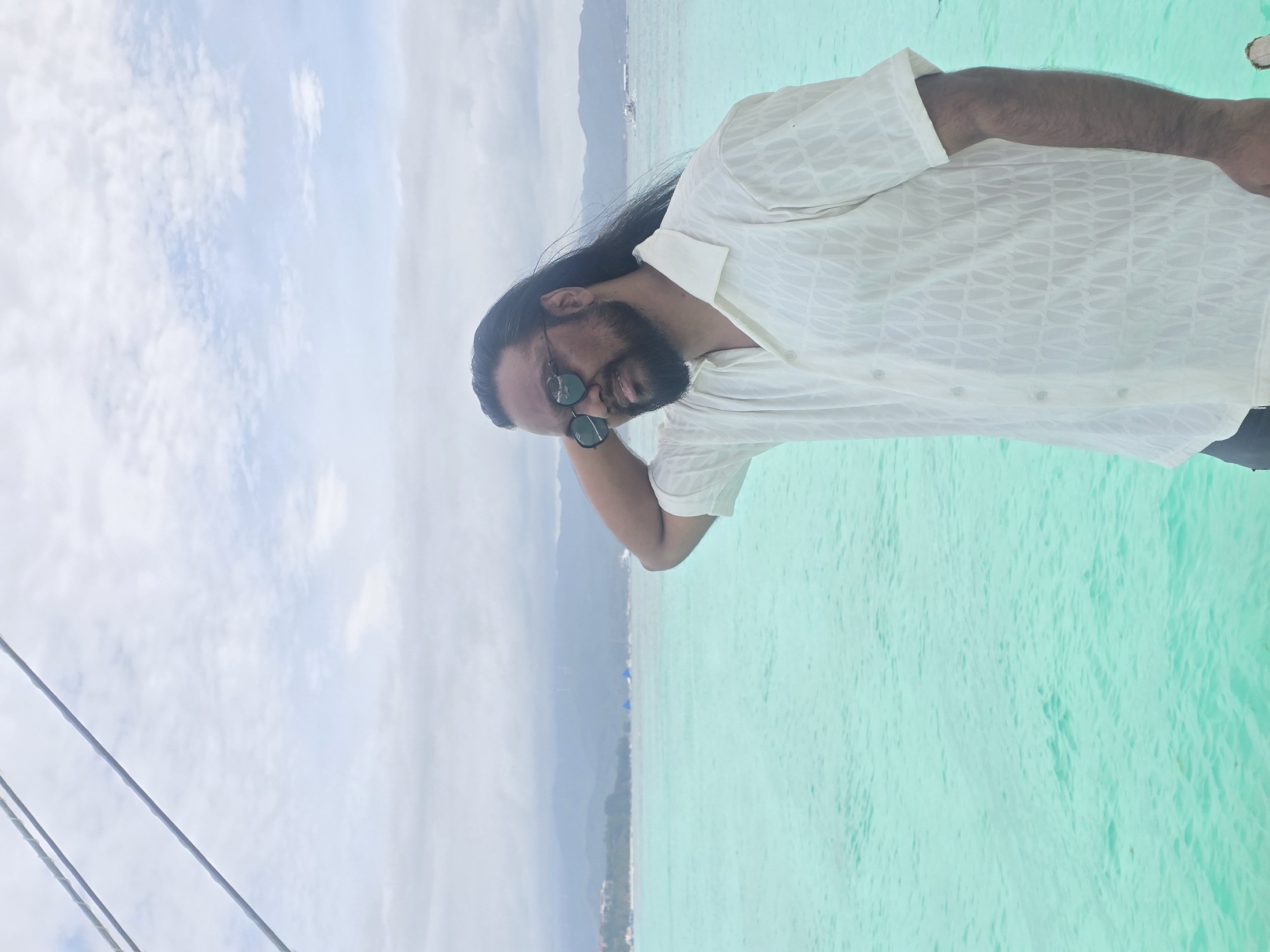 Suniv Ashraf beside a wide turquoise sea horizon.