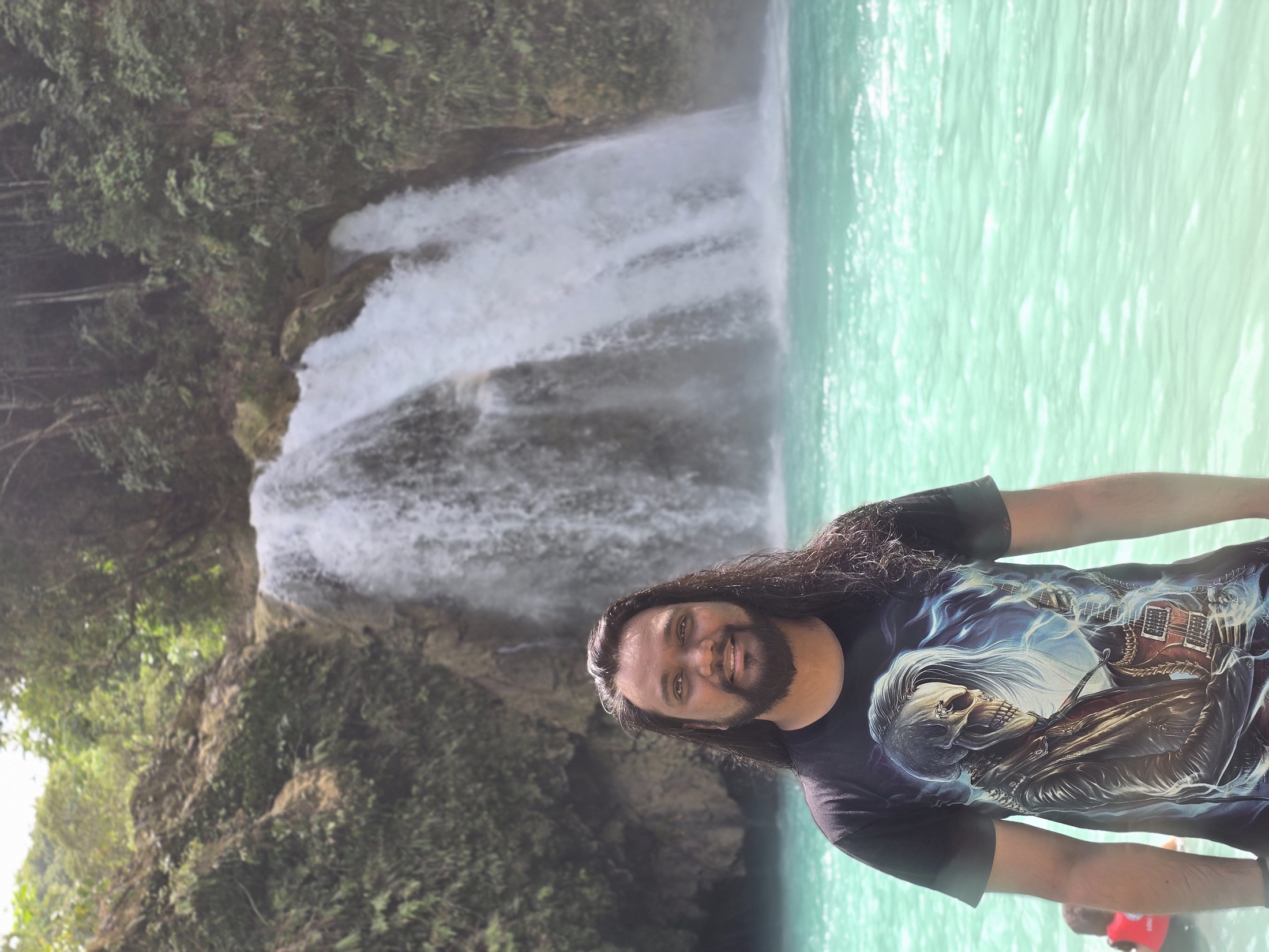 Suniv Ashraf in front of a waterfall and turquoise water.