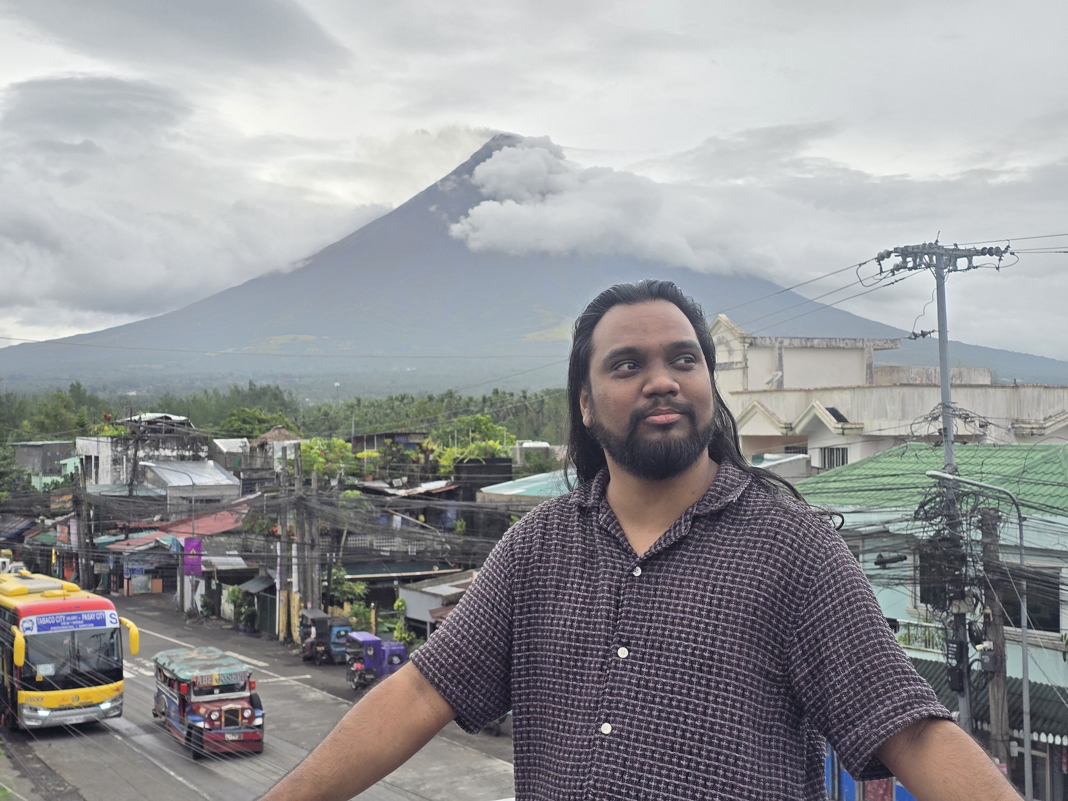 Suniv Ashraf before a cloud-covered volcano and town.